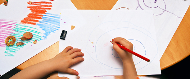 Två barnhänder ritar på ett papper.