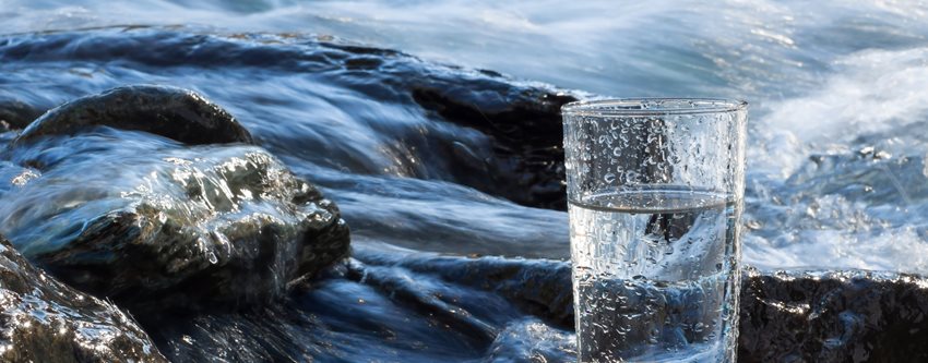 Ett glas vatten står på en sten i strömt vatten